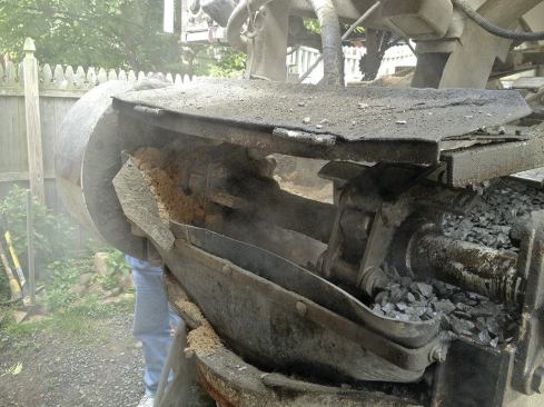 Cement and water pre-mix with the sand and stone as they pass through a funnel-shaped discharge chute at the end of the conveyor.