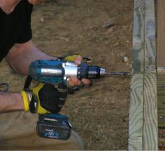 Figure 5. A heavy-duty drill and an auger bit make quick work of the bolt holes. The author drills 3/4-inch holes for 1/2-inch bolts to provide flexibility for shimming the post plumb.