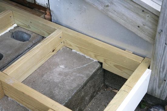 We installed a double ledger along the house, pitched slightly from the inside corner of the porch, and attached hangers for every joist. To maintain an adequate slope away from the house, I had to notch some of the joists where they crossed the block foundation.