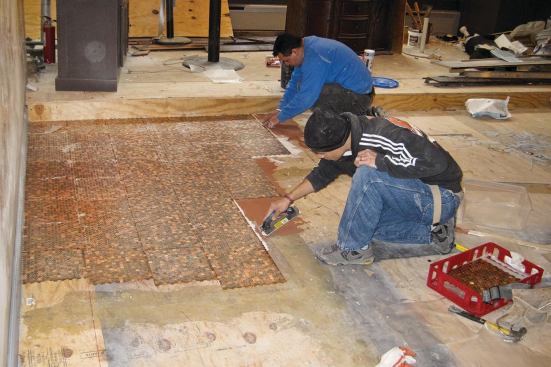 Spread a thin layer of Latapoxy adhesive on a section of the prepared plywood subfloor. It should be thick enough to make the pennies stick securely to the floor, but not so thick it smears their exposed faces. Working fast, turn a “tile” of pennies onto the epoxy and press it into place. Once the resin has cured, peel off the plastic film. Repeat several thousand times.