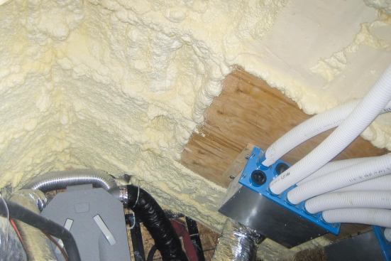 The roof framing in the attic mechanical room is encapsulated in a thick layer of closed-cell spray foam, bringing all the hvac equipment and ductwork within the building’s thermal envelope. Plywood panels, fastened to blocking before the foam was applied, provided solid mounting surfaces where needed. To meet the fire code, the exposed foam was coated with intumescent paint.