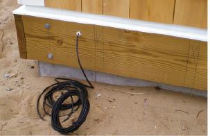 Figure 3. The author usually pulls the speaker wire through a hole drilled in the ledger before the deck is framed and leaves a long length coiled and ready to be run to the speaker locations.