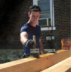 The author finishes rough-sawn cedar for a pergola, prior to assembly. That way, he can work on the ground; also, no surfaces are buried in joints and hidden from the brush.