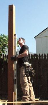 The posts are left long, placed in holes, and plumbed in two directions prior to backfilling.