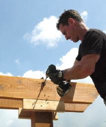 While the girders are temporarily supported on cleats, pilot holes are drilled; the girders will then be bolted to the posts permanently.