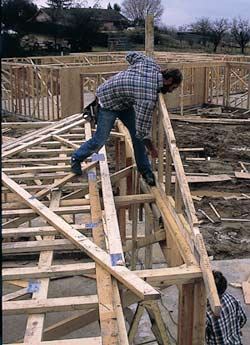 Figure 2. With the upright braces in position and toe-nails started along its bottom chord, an end truss is tipped into position and nailed off. On taller trusses, the author preinstalls the top outriggers to avoid later hassle.