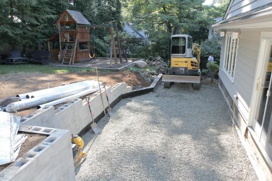 PVC pipe and crushed stone drain the wall. The ground below the deck was graded toward the wall, and then covered with crushed stone.