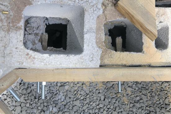 Epoxy anchors and bolts secure the ledger to the retaining wall.