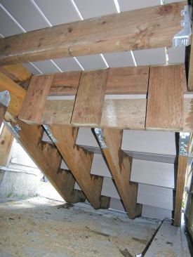 A 2x8 the width of the stair is supported by scraps of framing lumber. Commercially available hardware secures the jacks to the 2x8. 
