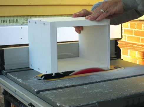 The base comes first, and I rip the widths I need and cut them to length. As before, I glue and screw three sides together and screw on the fourth side temporarily. I bevel the top of the base to shed water, so while it's still all together, I set the bevel angle on my table saw and run the piece through on all sides.