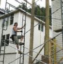 The crane lightened the burden, but still the author had to rig the bundles of lumber on the ground and climb the scaffold to guide them into place.