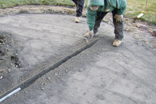 Lengths of one-inch-diameter conduit are set into the compacted base to serve as screed guides.