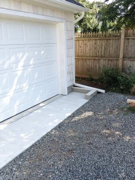 The exposed block stem wall was parged with mortar, and the driveway was regraded with new gravel. Gutters were added, and a berm was created to help direct runoff away from the entry apron.
