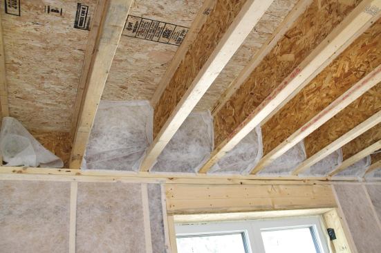 Netting stapled between the joist ends is filled with cellulose to form insulating and air-sealing “pillows”.