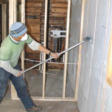 Filled cavities are compacted with an aluminum roller to avoid bulging drywall. A quick pass of the hand is enough to confirm that the insulation lies flush with the framing.