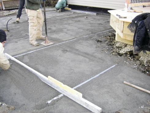 After adding stone around the guides, the crew screeds and tamps the surface.