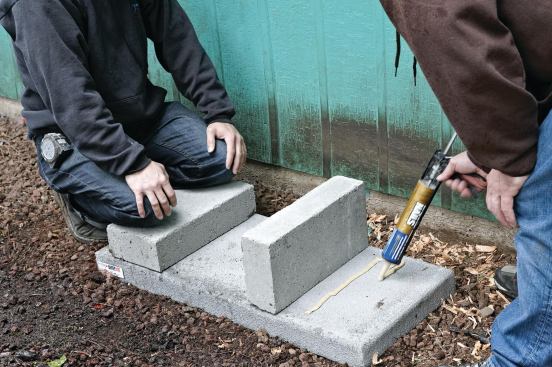Concrete riser blocks — which elevate the outdoor unit to provide drainage — are fastened to the pad with construction adhesive. 