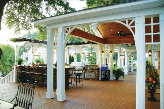 A country-style porch overlooks an outdoor kitchen. Both were built by Paradise Decking (paradisedecking.com) in Summerfield, N.C.