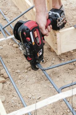 The tool’s jaws fit around the rebar, and when you squeeze the trigger, the machine ties and cuts the wire.