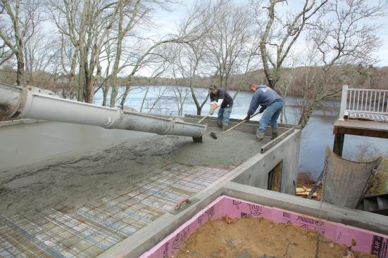 Working with an engineer, I decided to pour a concrete slab on top of metal deck pans supported from below by steel I-beams. The design called for 10-inch-thick reinforced foundation walls formed with beam pockets and a perimeter shelf to support the steel pans. Two W12x40 I-beams would span front-to-back below the deck pans to support the reinforced slab.