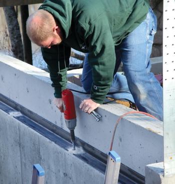 A worker bolts the steel angle to the perimeter shelf.