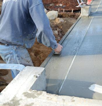 To create a weather lip at the garage doors, the foundation contractor sinks a length of galvanized pipe into the wet concrete (A), then finishes the sloping apron in front of it.