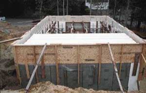 Perimeter forms were required to contain the edge of the poured floor system. Subfloor panels served temporary duty as form panels, attached in the same manner as the wall brackets, using 16-inch LogHog screws and 2x4 backers. Plywood scraps pack out the bottom of the vertical braces to hold the panels flush and parallel to the outside wall surface.