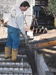 A triangular wood screed strip attached to the wall form guides the thickness and slope of the floor and provides a beveled edge to the finished slab.