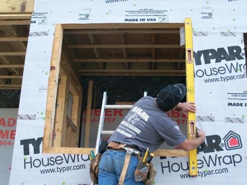 Assuming that housewrap is present and properly installed, the first step is to cut it back from the rough sill and side jambs about 3 inches, or the width of a level.