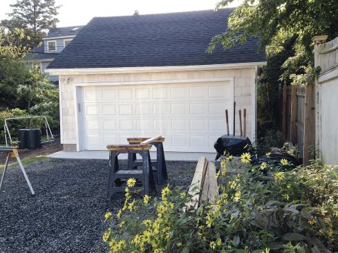 The bulk of the exterior finishes are on the front wall; new siding flanks a car-and-half-wide garage door.