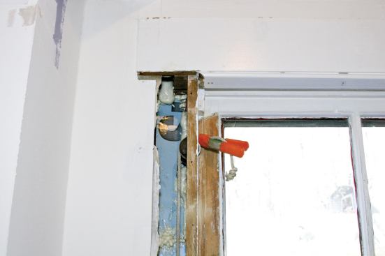 A spring clamp prevents the sash cord from dropping into the pocket; on the window shown, the trim was in bad shape and was removed for replacement, allowing the author to insulate the cavity with XPS and spray foam.