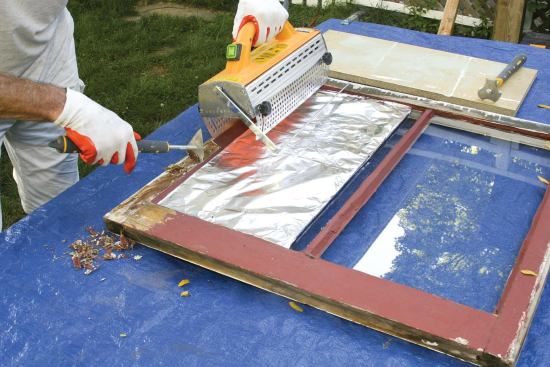 To improve the window’s operation, old paint is removed from all running surfaces; here the author uses an infrared paint-stripping tool.