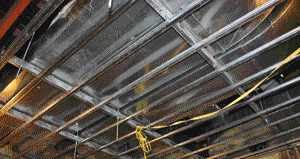 On the ceiling of this room, spring isolators support heavy-gauge steel framing that will ultimately be covered with a layer of 3/4-inch plywood, a layer of mass-loaded vinyl, and then drywall. Multiple pipes and ducts didn't leave a lot of room for regularly spaced mounting hardware in this high-end home theater, so spring isolators — which generally have a higher load capacity than other types of isolation hardware — were a good choice.