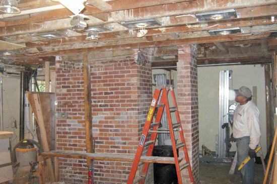 Once we had the beams in the basement, the welder had to do some fabrication — cutting to length, drilling holes for connections, and welding on web-stiffeners at various bearing points. Our brick mason had assured us that the brick chimney would behave monolithically, so that we could install the beams one side at a time without risking collapse.