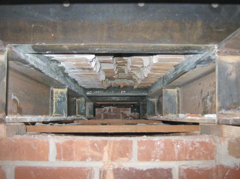 We also welded a 5-foot length of 6-by-1/4-inch steel plate along the top flange for securely attaching the brick mass above to the I-beam. The steel  plate was predrilled every 8 inches so that we could embed and epoxy 5/8-inch threaded rod anchors directly into the brick. Once the steel plate was installed, we repeated the whole process on the other side of the chimney with the second 18-foot beam. Next came some pieces of steel angle  that spanned the 30 inches between the I-beams at each end of the chimney. These short members were notched into the brick above and grouted so that they picked up more of the load.