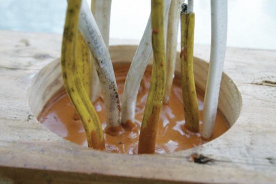 “Puddle sealing” involves using a 4-inch hole saw to make a hole in the bottom plate where multiple wires will run through the subfloor, and pouring a fluid sealant around them.