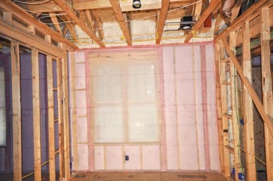Once the air-sealed framing is covered with staple-up netting, the cavities are filled with blown fiberglass, which the author finds more reliable than batts. According to the manufacturer, the latex sealant is designed for use with either material.