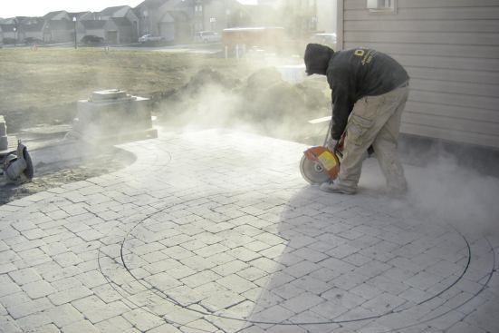 To create clean borders for inlays, all field pavers are set and compacted, then the pattern is cut out.