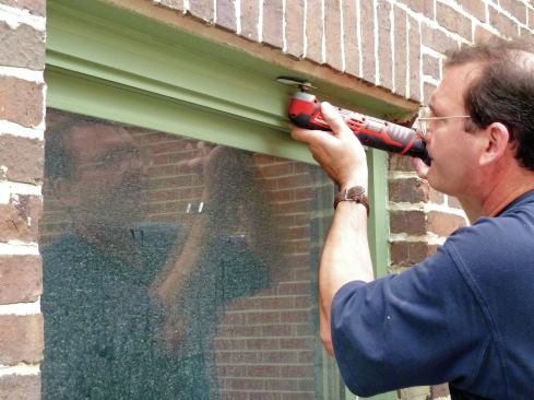 To remove the old window, first separate the trim from the opening by cutting through the old caulk with an oscillating tool.