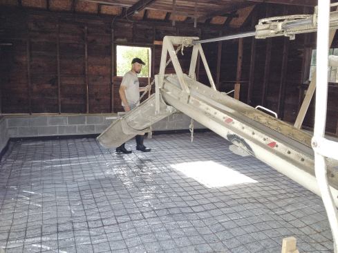 After laying down a layer of 4-inch gravel, reinforced 6-mil poly sheeting, and welded-wire mesh, the crew ran asphalt-impregnated fiberboard around the inside face of the footing.