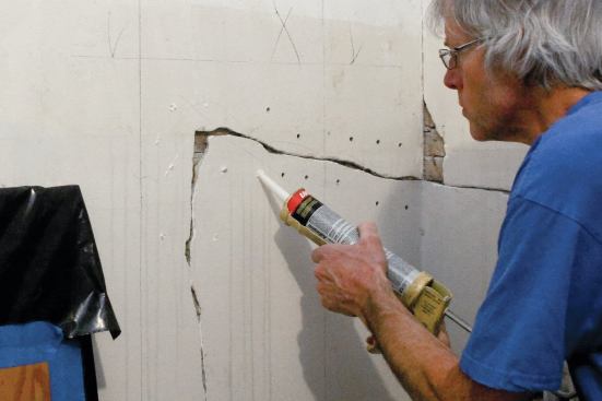 Start by drilling a series of 1/4-inch holes every few inches, being careful to drill through the plaster without penetrating the lath. After vacuuming out the dust, squirt a little water into each of the holes, then inject the adhesive until it oozes out around the edges of the tip.