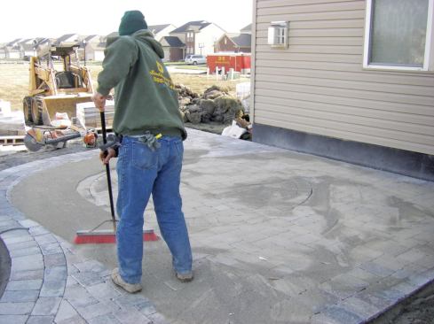 Mason sand swept across the finished surface fills the joints between pavers. 