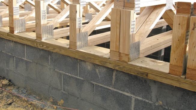 After installing the trusses, we scribed the 2 3/32-inch rim material to fit. To make sure there would be plenty of bearing, we doubled up the rims where we had corrected for the out-of-square walls.