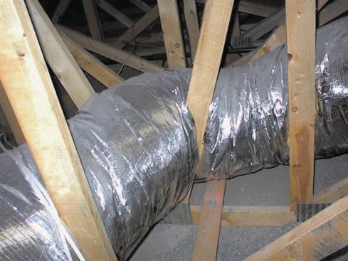 The duct shown in the photo at left fails on two fronts: 1) It runs through the attic, which may be the most stupid place you can put ducts in an air-conditioned home. 2) The duct run is pinched where it passes through the truss webs. This constricts airflow, increasing duct pressures so the conditioned air carried in the duct flows out of the leaks faster.