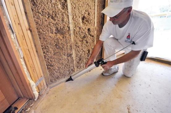 Note how the ceiling above the doorway has been insulated with open-cell foam. Cracks between the slab and bottom plates are sealed with flexible caulk.