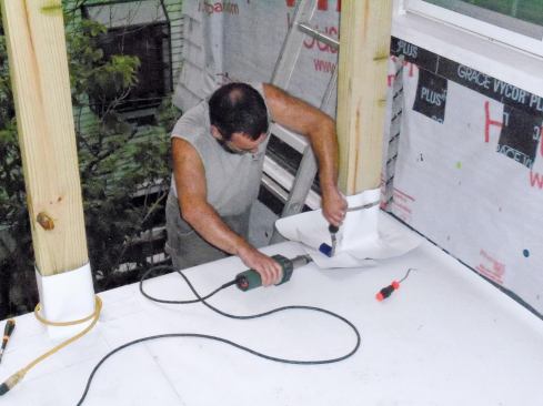 Square-sectioned flashing boots are temporarily secured with provided band clamps before being welded to the deck with the heat gun and roller.