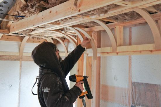 The arches were fastened to the furring strips 16 inches on-center. A narrow crown stapler and dabs of construction adhesive were used to make the attachment.