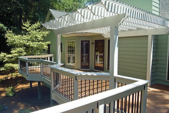 Arbors built from framing lumber create shade and define outdoor rooms. Scroll cuts on the ends of the beams and joists provide interest, and attachment to the house provides rigidity.