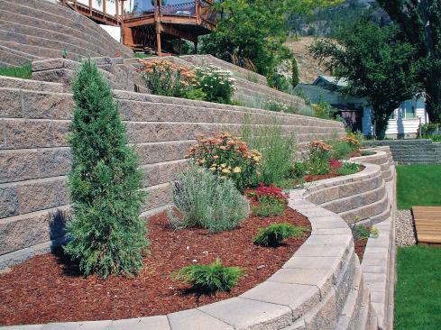 The first segmental retaining wall you build likely won’t look like this, but the photo illustrates the design possibilities offered by these versatile systems, including curved walls and planting areas. 