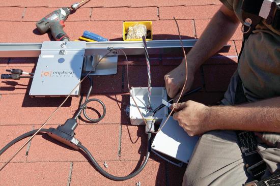 After manufactured module interconnection cables are laid out on the roof, a locking waterproof plug at each microinverter is snapped into the adjacent cable fitting, and the cable is connected to the metal-clad cable and module ground wires at the junction box.